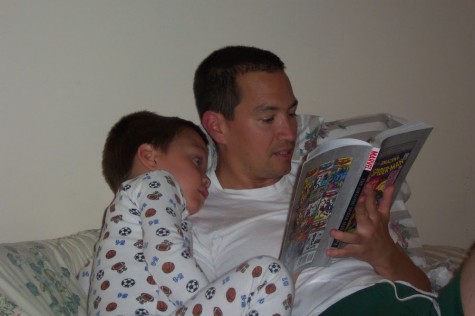 Christopher listens intently while his father reads a comic book to him.  