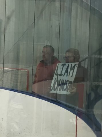 Indian Hills student holding a “Liam Johnson” sign against the glass for Johnson and all to see.