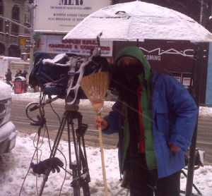 A broom can be very helpful while shooting in a blizzard. Here in Times Square in 2011 while the snow piles up.