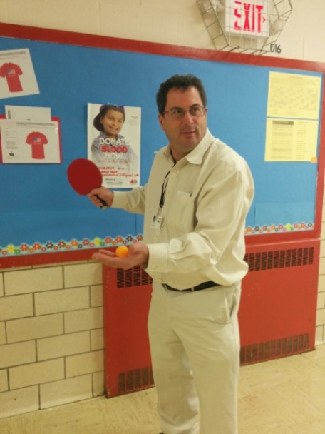 Mr. Feldman uses his own paddle to demonstrate tossing, grips, and proper techniques in table tennis.