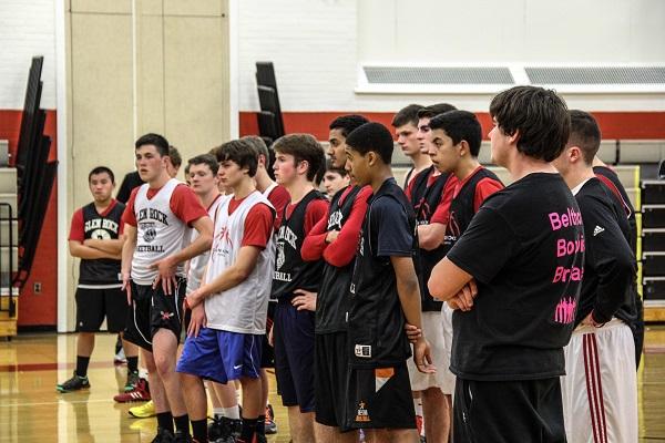 The basketball team at practice listening to the coaches.