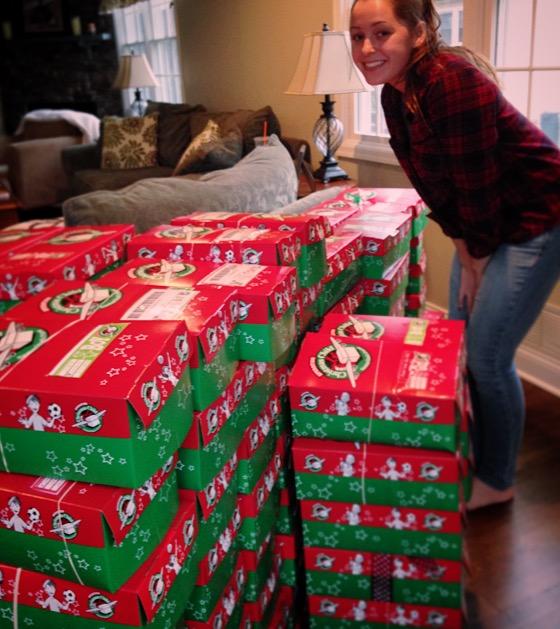 Colorful shoe boxes filled with goodies ready to be donated to Operation Christmas Child. Chelsea Blind, senior, stands with the gifts she helped to collect, organize and send off to children in need.