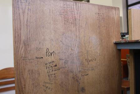 A great amount of graffiti can be seen on the desks in the back of the media center