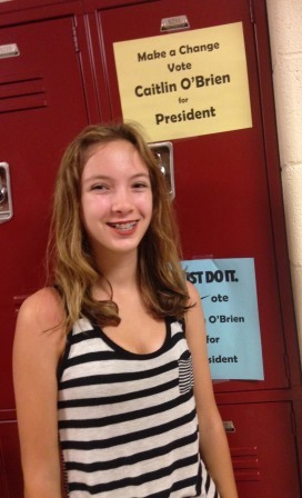 Presidential candidate Caitlin OBrien beside her campaign posters hung in the freshman hallway