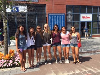 Players of the girls’ varsity tennis team pose in front of an entrance to the U.S. Open.