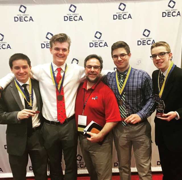 Valedictorian Chris Theuerkauf (far left) at DECA states earlier this year smiles with classmates and teacher Frank Manziano, one of his many extracurricular activities.