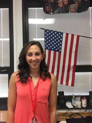 Drew Forgash smiles for a picture under the American Flag in a history room