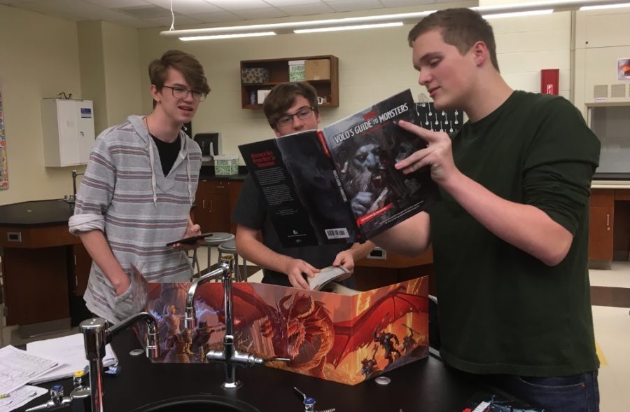 Members Francis Atler, James Ring, and Justus Smith consult Volos Guide to Monsters before continuing a Dungeons and Dragons campaign.