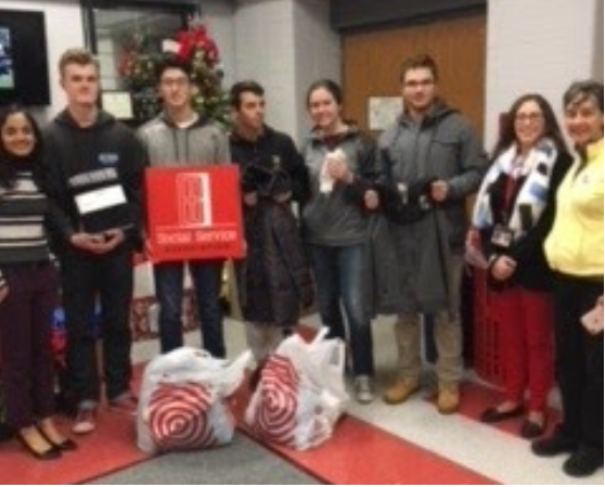 Students pose in front of gift drive presents. 