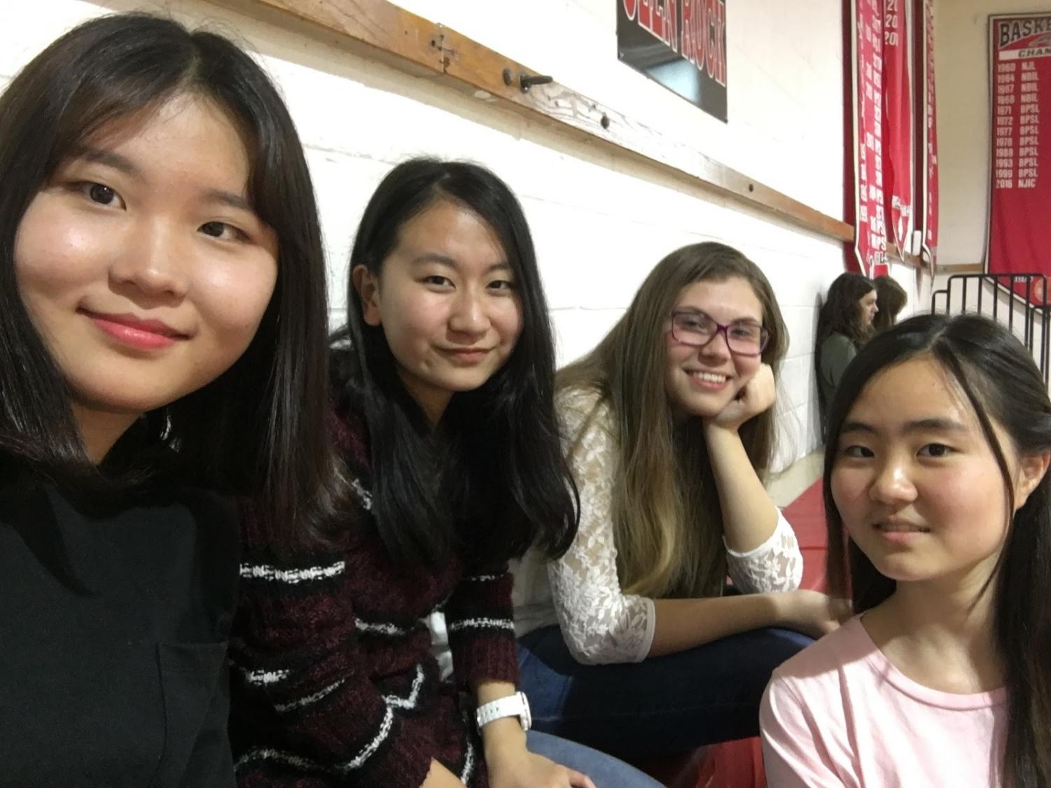 Hailey and her friends are posing in the gymnasium who are from Japan, Korea, and Slovakia. Hailey met her friends when she first moved to Glen Rock and became close friends with them.