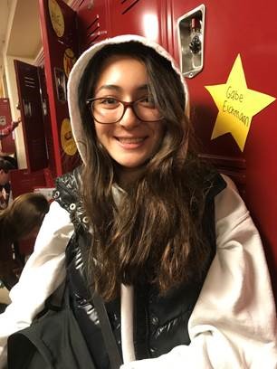 Dzurenko poses smiling at the camera as she packs her backpack at the end of the school day to get ready for a night of homework.
