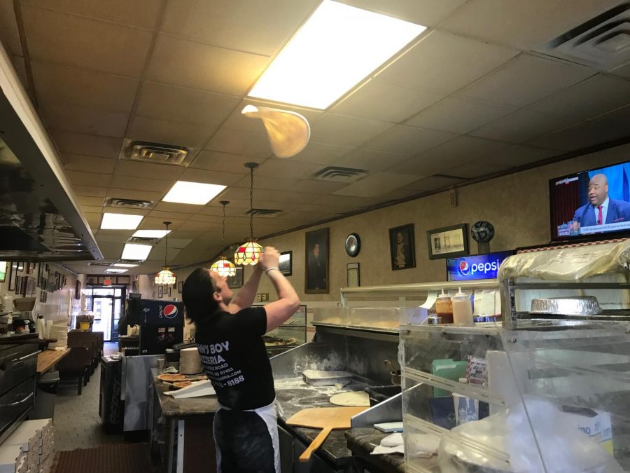 Umberto throwing the pizza dough in the air as he prepares to make a pie for a customer.