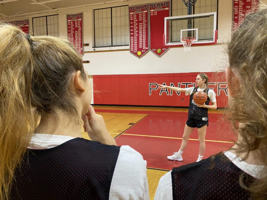 Before practice begins, Abby explains an offensive play to the juniors on the team.