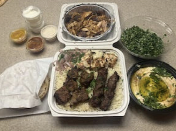 (top down left to right) garlic butter, turmeric sauce, chili sauce, tahini sauce, meat shawarma, tabouli salad, pita bread, Taste of Haifa platter, hummus
